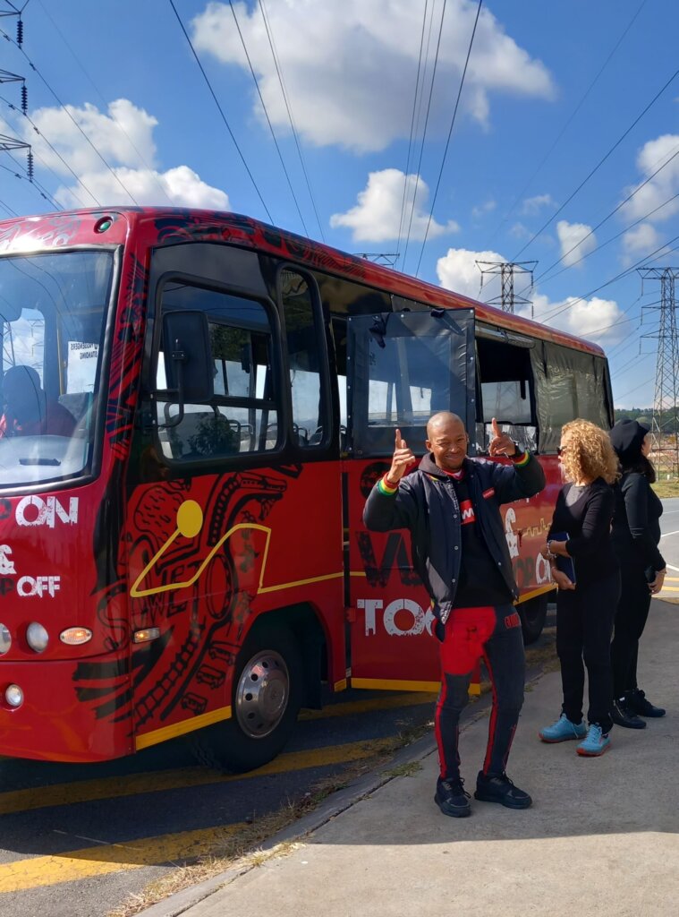 This photo shows DT giving a double thumbs-up standing next to our minibus