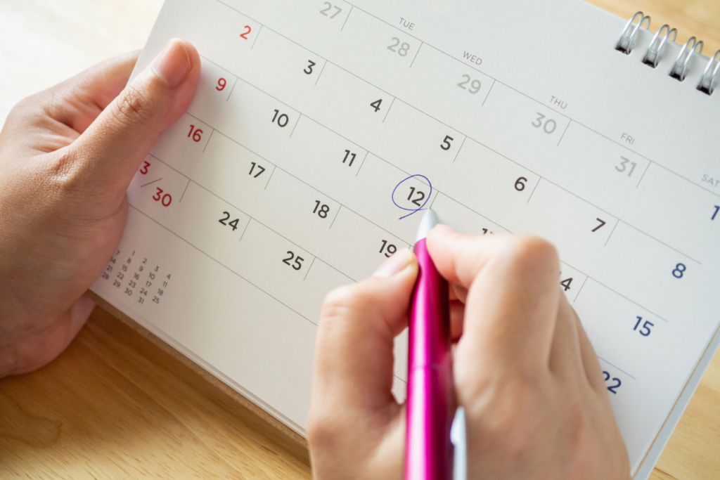 This photo shows someone planning when to start their trip. They are holding a calendar and circling a date.